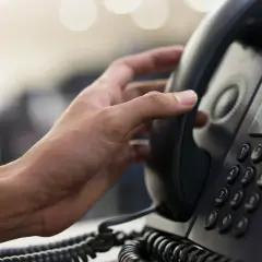 Hand hält ein Telefonhörer für eine audio conference.