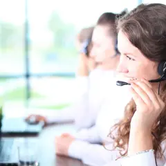 Callcenter-Mitarbeiterin mit Headset, die lächelt. Kundenservice ist ihr mos wert.