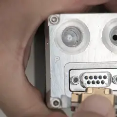 Nahaufnahme eines metallischen Geräts mit einem D-Sub-Anschluss, an den ein Stecker angeschlossen wird.