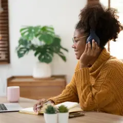 Junge Frau mit Kopfhörern lernt online, ohne Jitter-Definition. Sie notiert sich etwas, während sie auf den Laptop schaut.