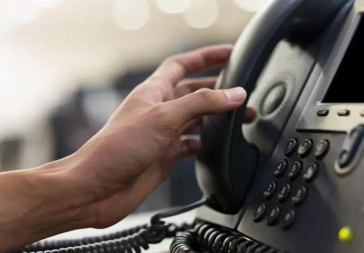 Hand hält ein Telefonhörer für eine audio conference.