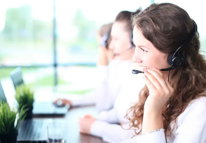 Callcenter-Mitarbeiterin mit Headset, die lächelt. Kundenservice ist ihr mos wert.
