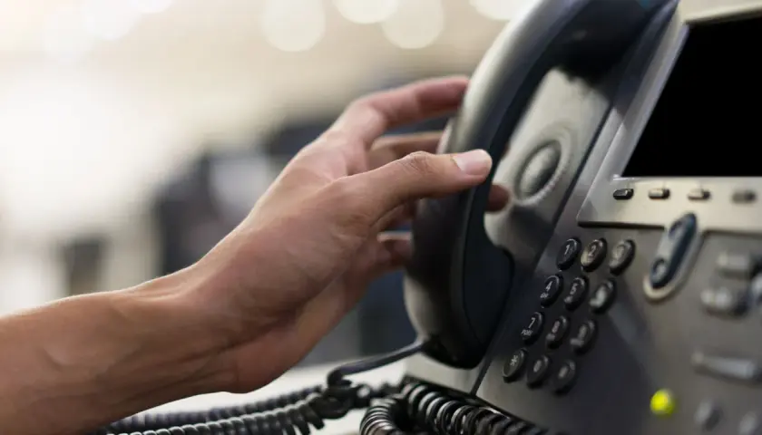Hand hält ein Telefonhörer für eine audio conference.