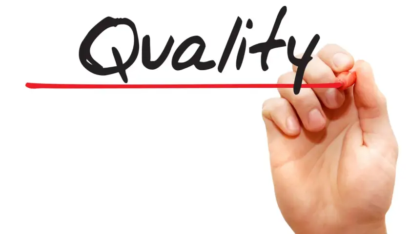 Hand schreibt "Quality" mit rotem Stift. Call monitoring für höchste Qualität.