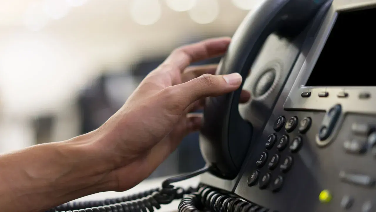 Hand hält ein Telefonhörer für eine audio conference.