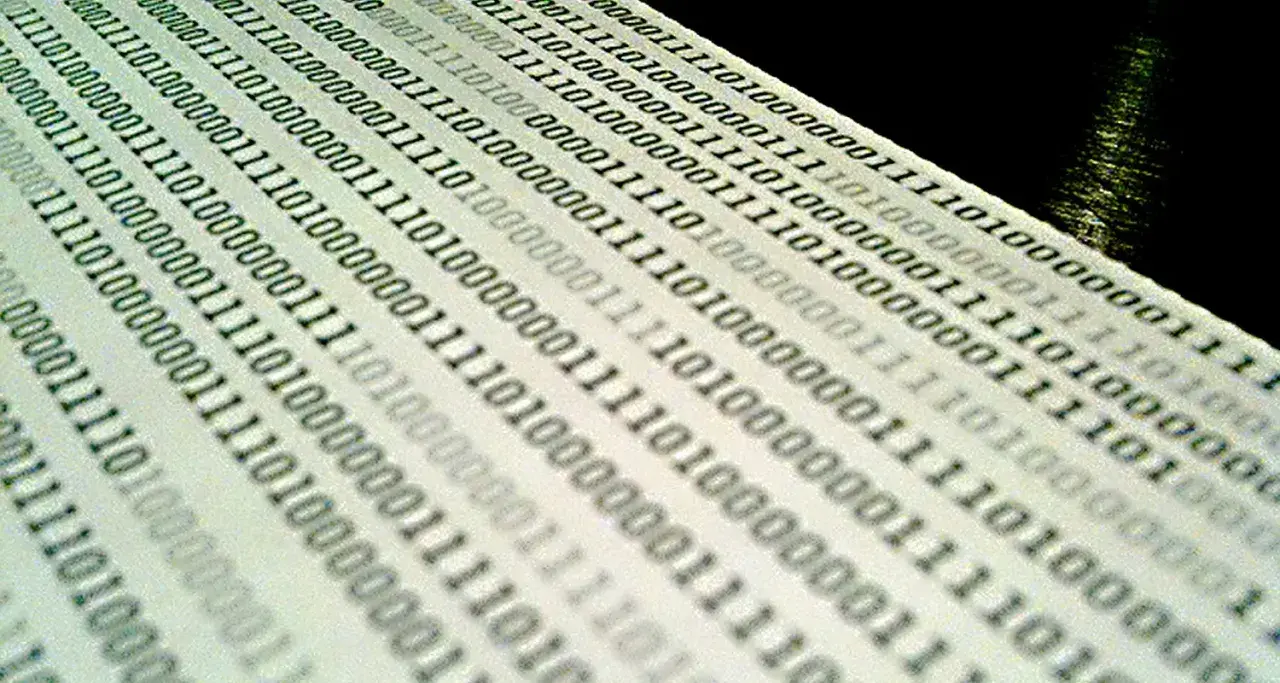 Binärcode auf Papier, der die Bedeutung von Jitter in der Datenübertragung veranschaulicht.